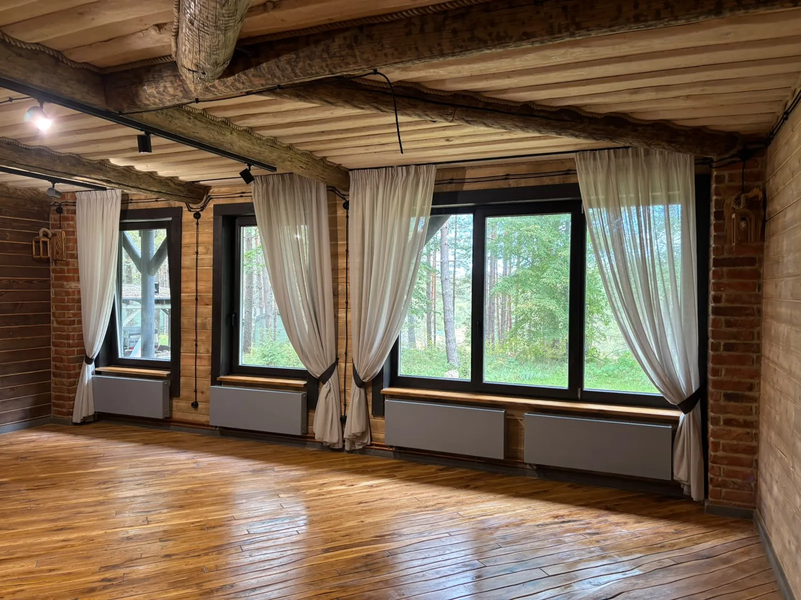 Sala com pavimento de madeira e grandes janelas